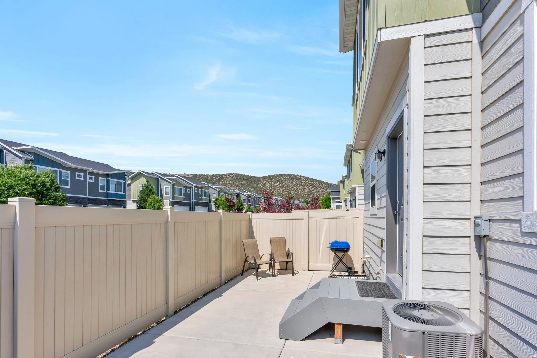 Private concrete patio featuring a beige privacy fence and gray siding