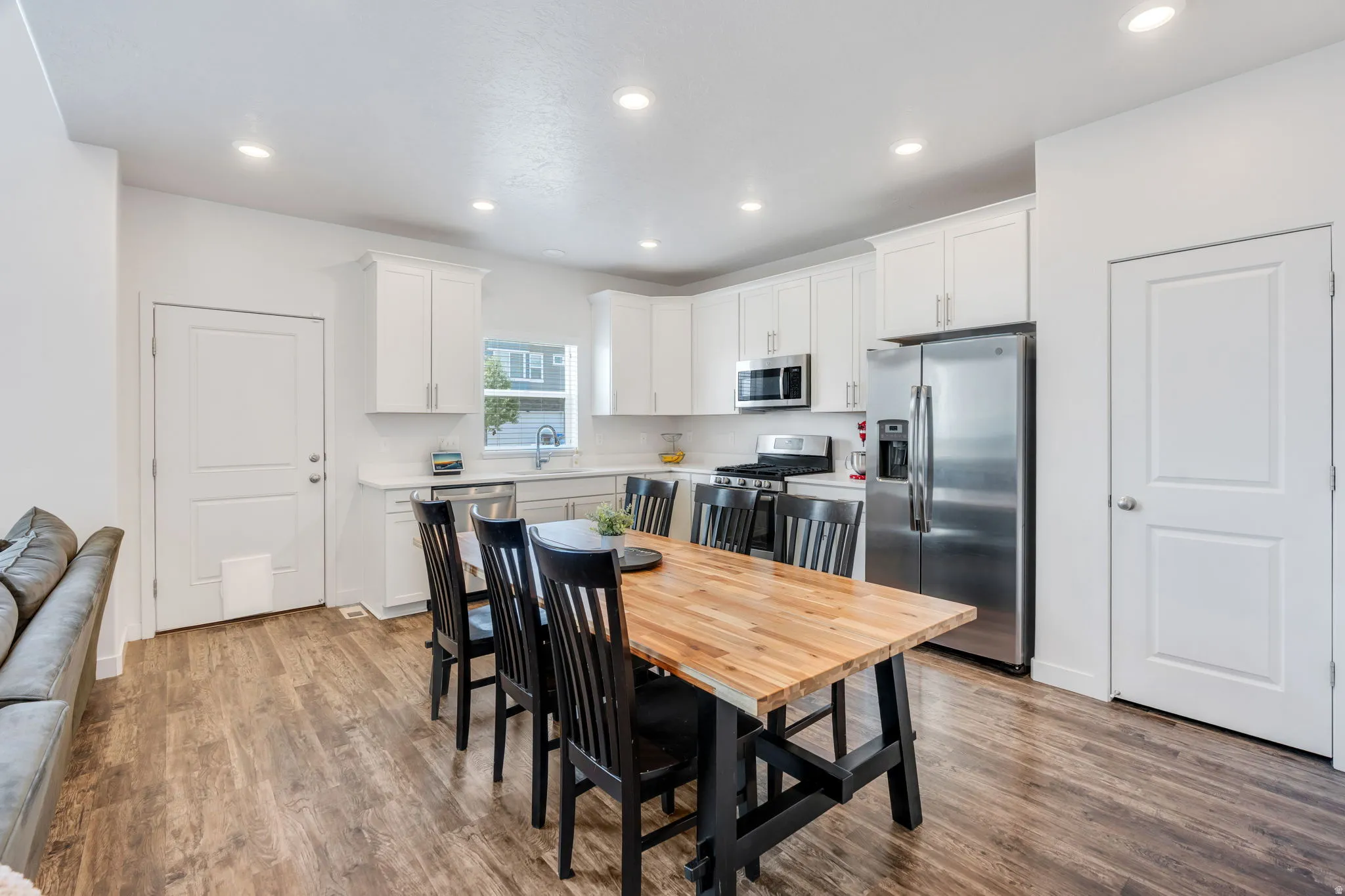 Open-concept kitchen featuring wood-finish flooring, white cabinetry, stainless steel appliances, and recessed lighting
