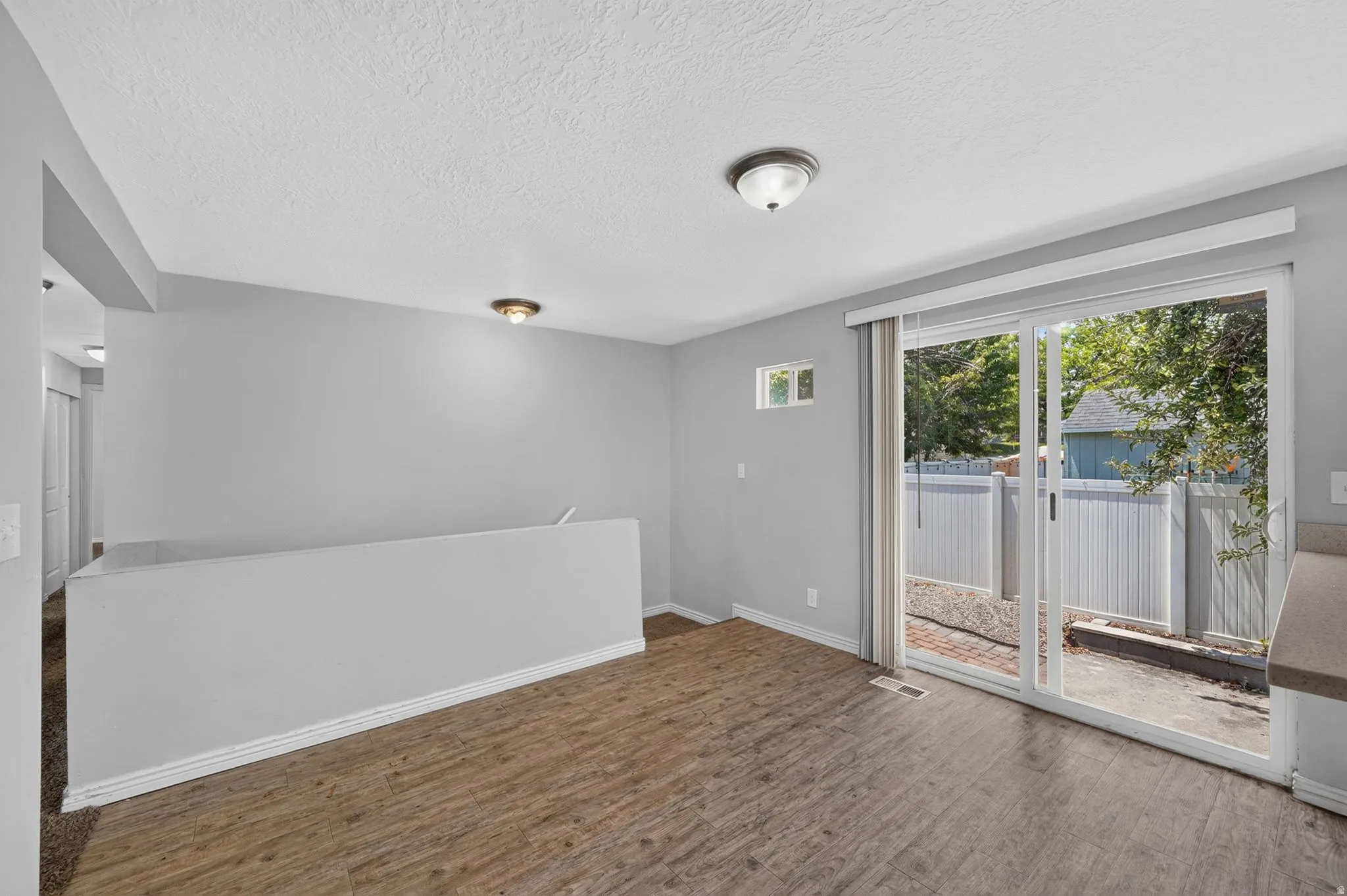 Spacious interior with wood-finish flooring, a neutral wall palette, and a half-wall partition