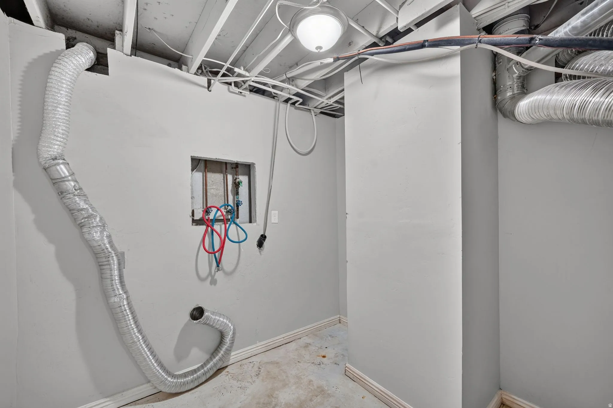 Utility area featuring exposed ceiling joists, ductwork, and wall-mounted electrical outlets