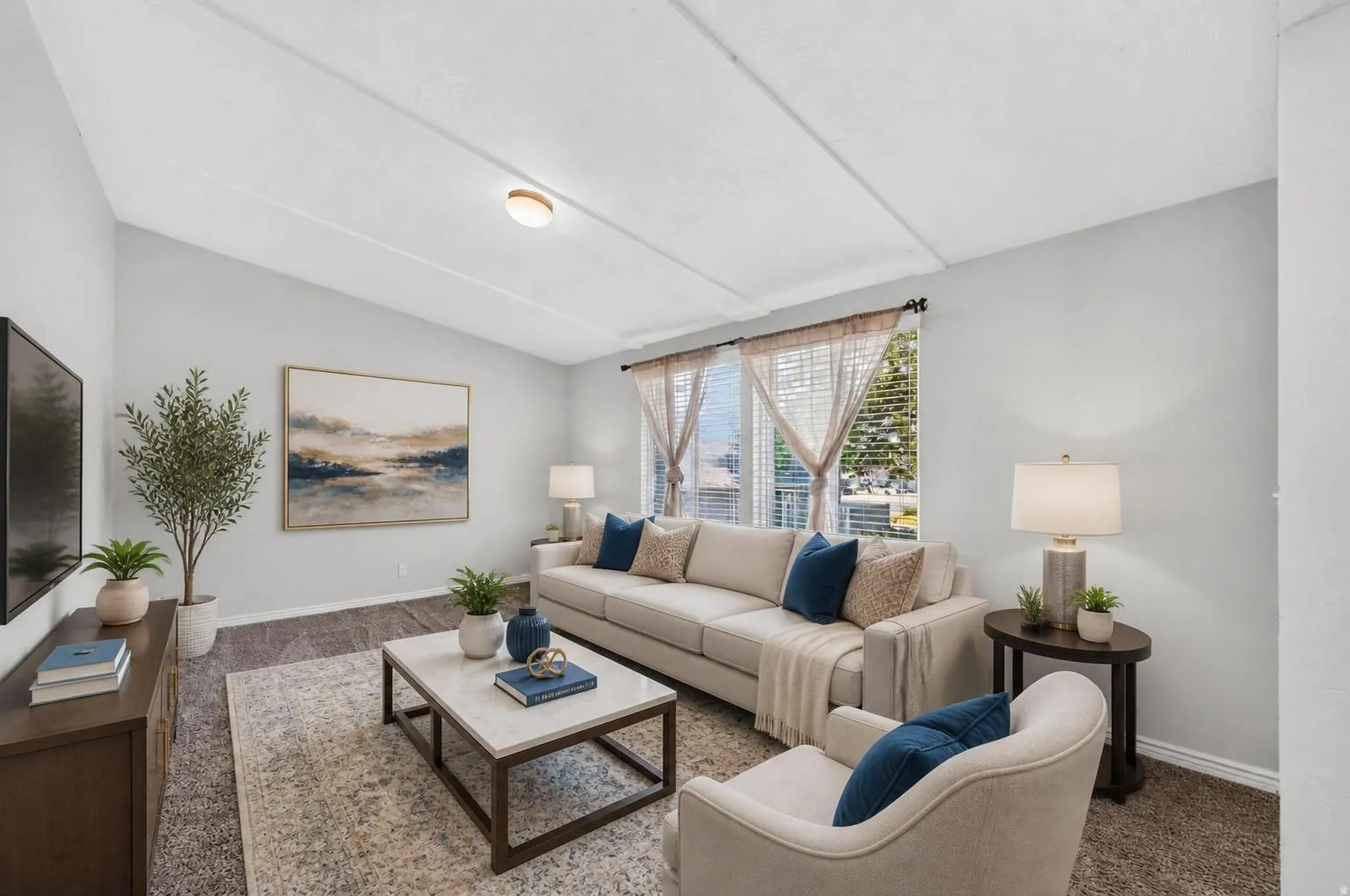 Spacious living area featuring light gray walls, wood-finish flooring, and a large window with privacy blinds