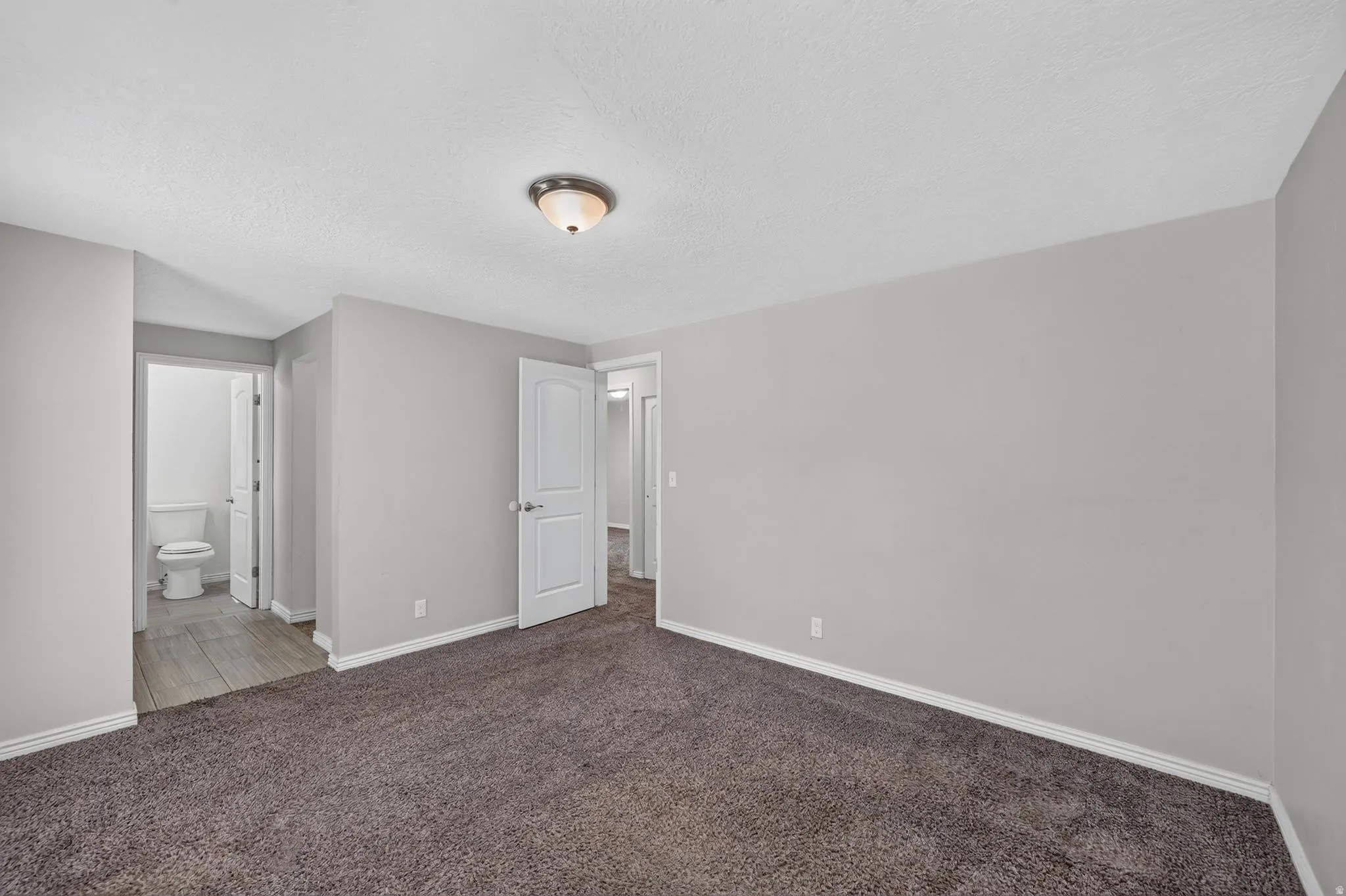 Carpeted room with light gray walls, white baseboards, and a semi-flush mount ceiling light