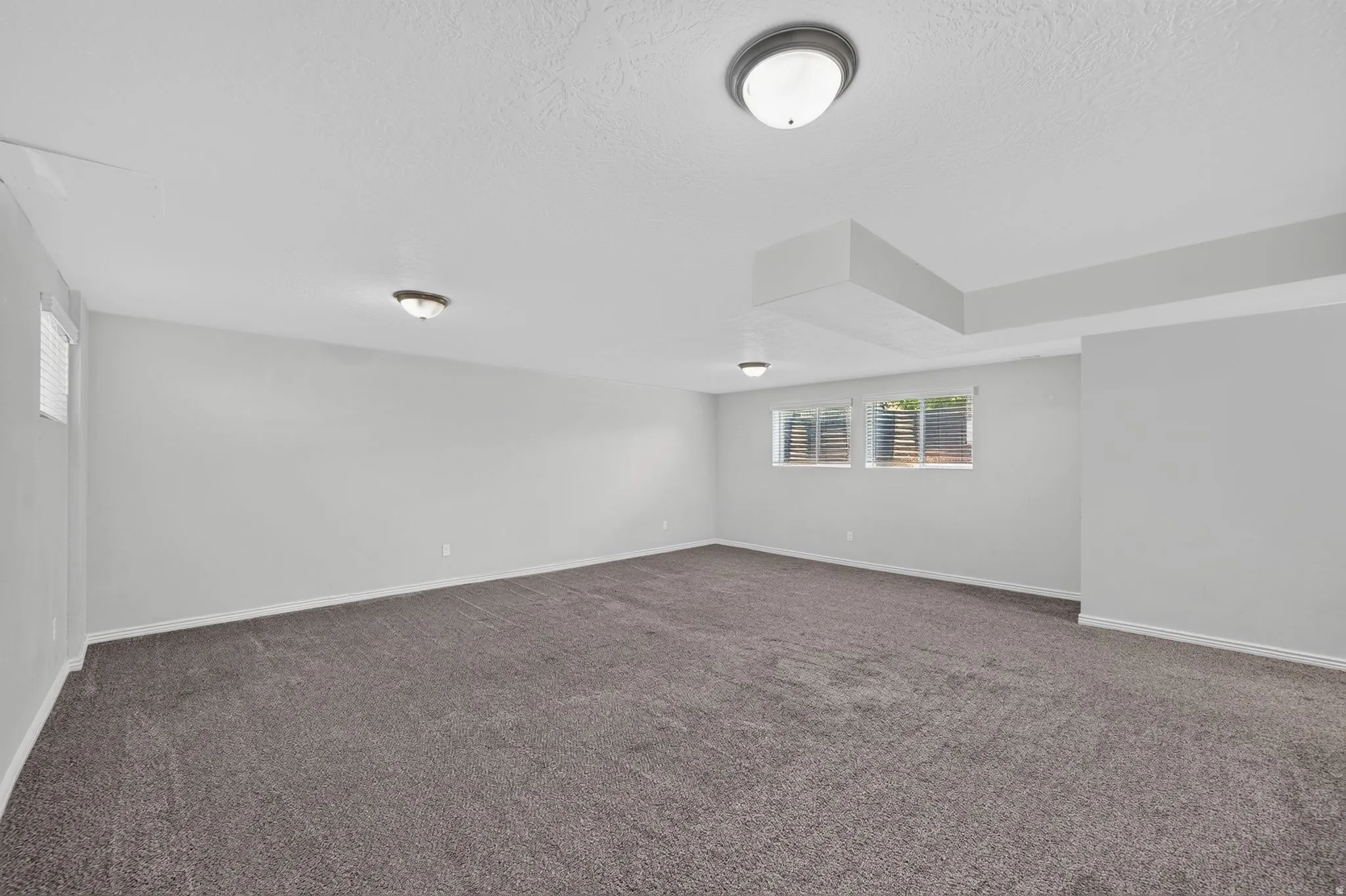Spacious room featuring neutral carpeting and light gray walls