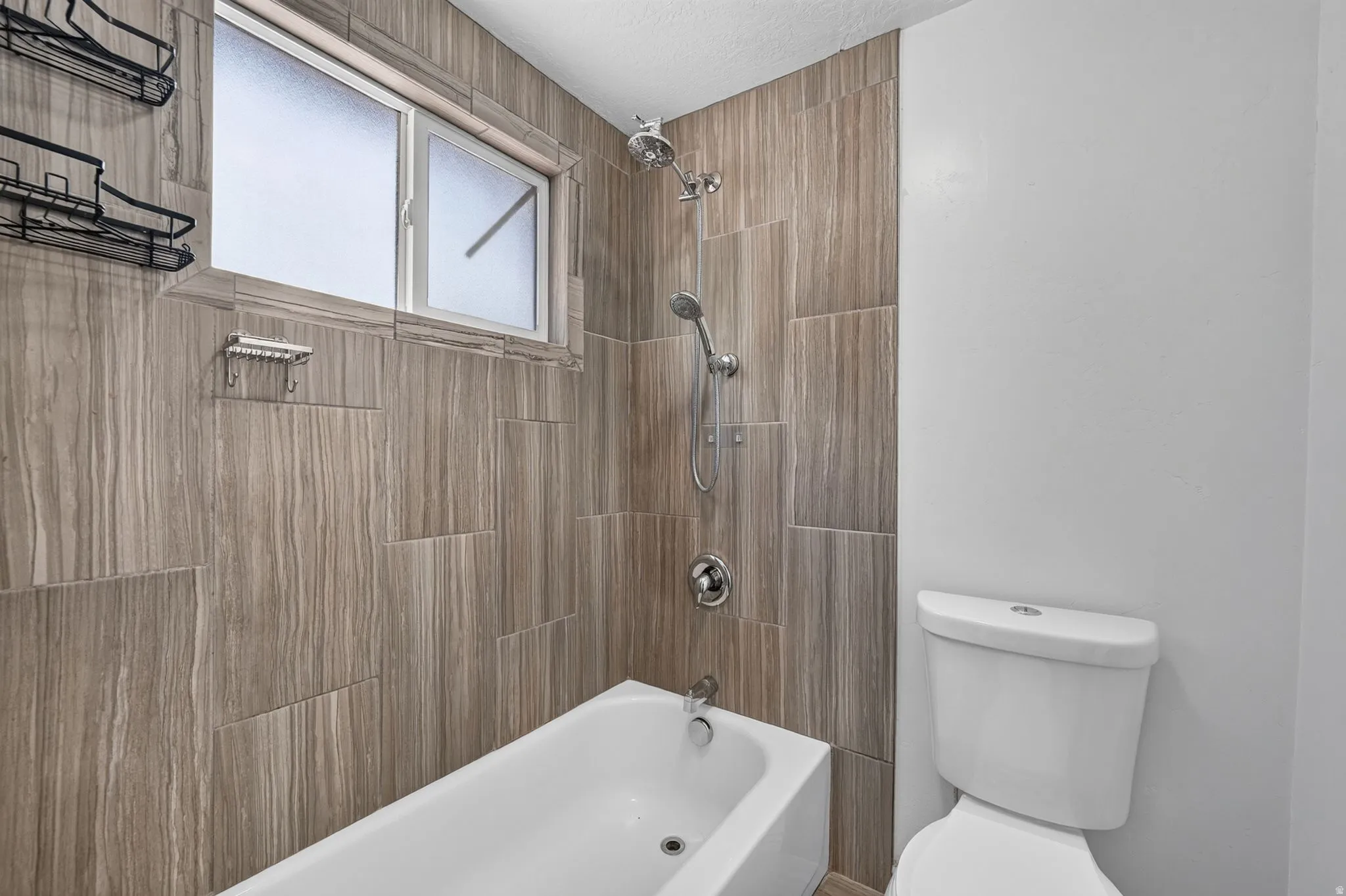 Family Bathroom featuring a white bathtub, wood-look tile surround, dual shower heads, and a frosted window
