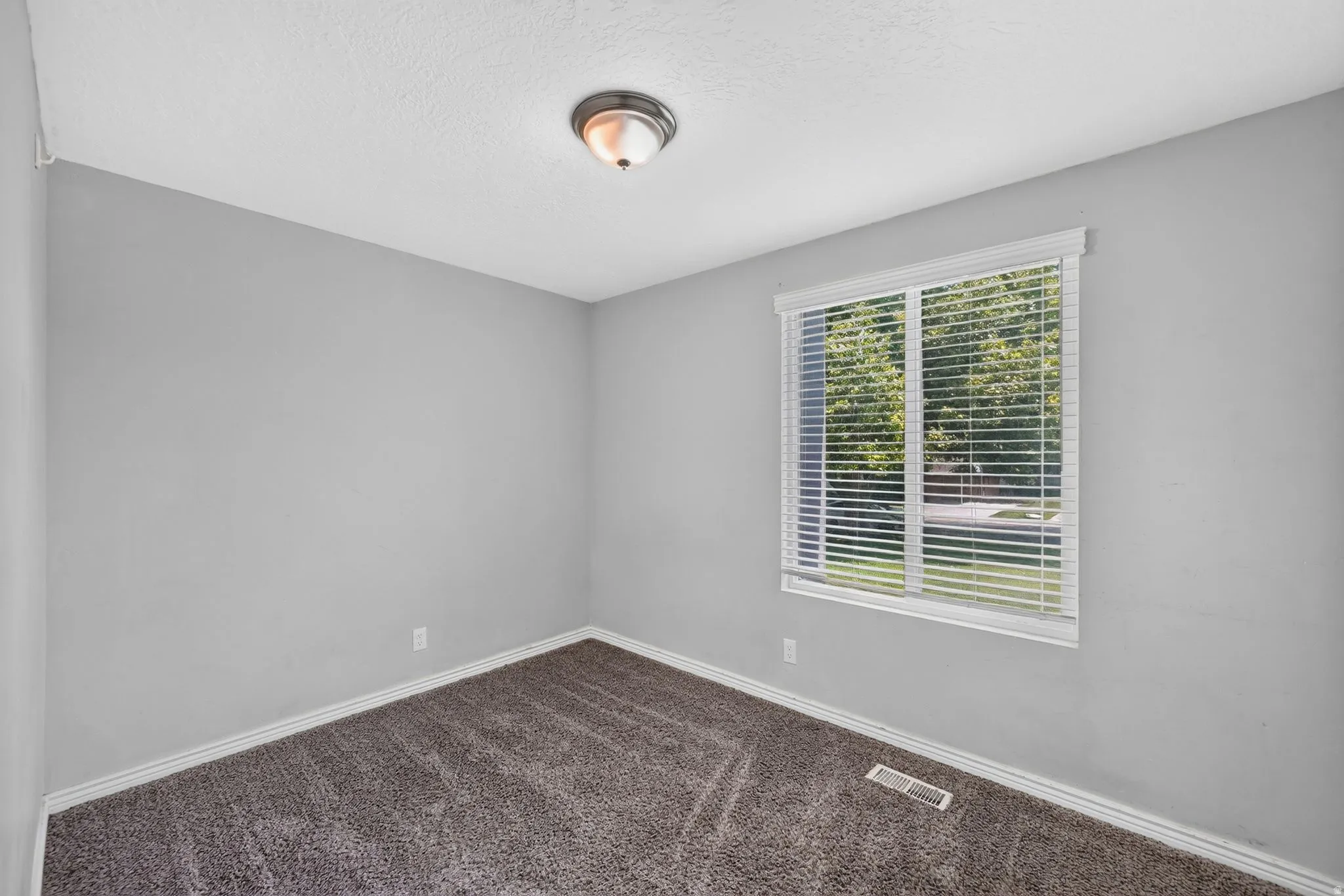 Room featuring light gray walls, gray carpet flooring, white baseboards, and a window with white blinds