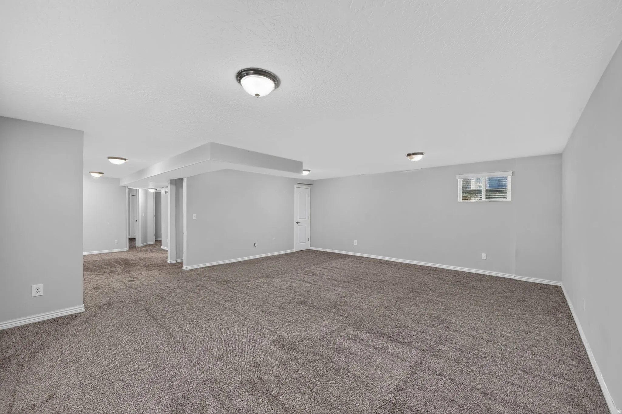Spacious interior room featuring neutral gray walls and new carpeting