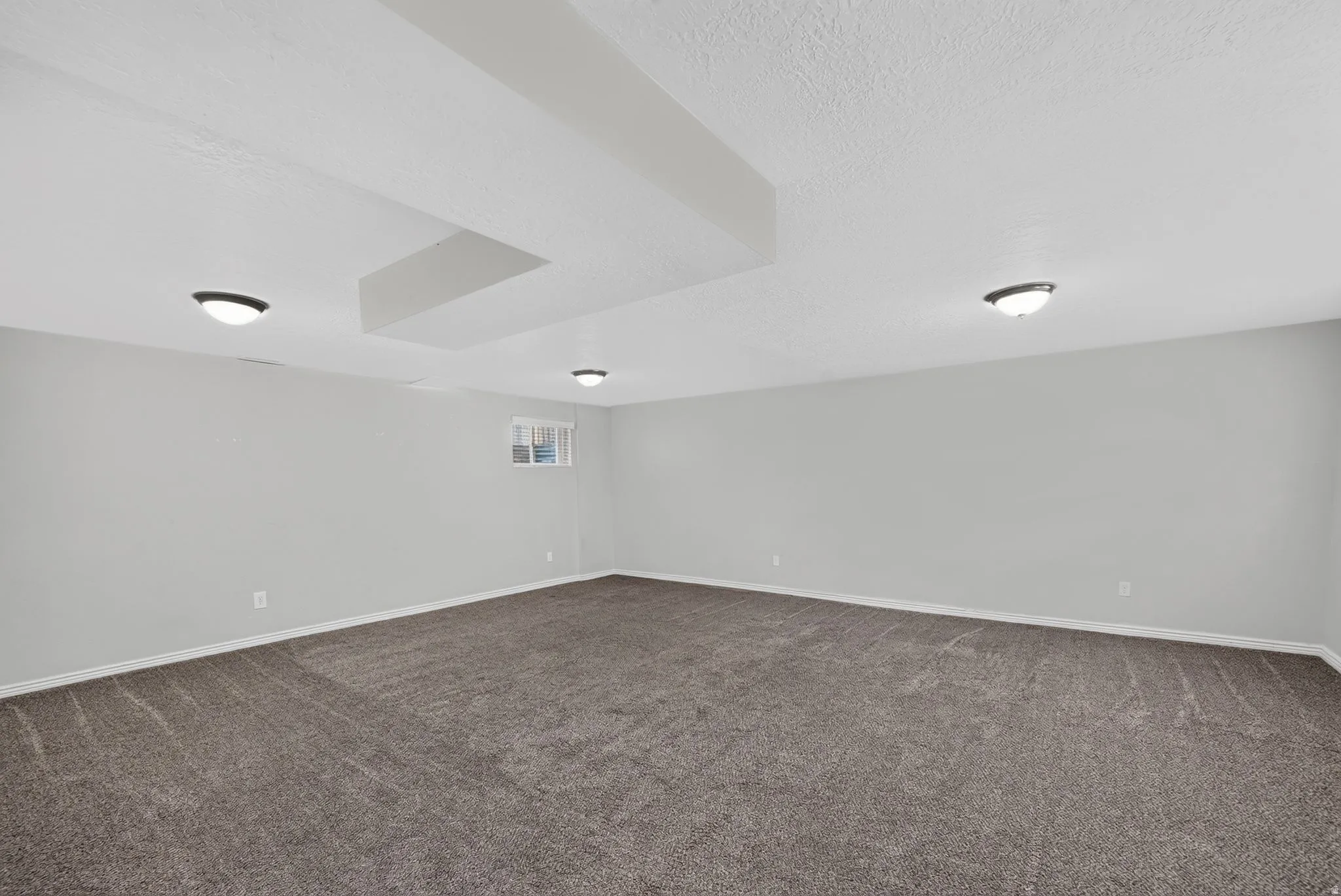 Spacious room featuring gray carpet flooring and light gray painted walls
