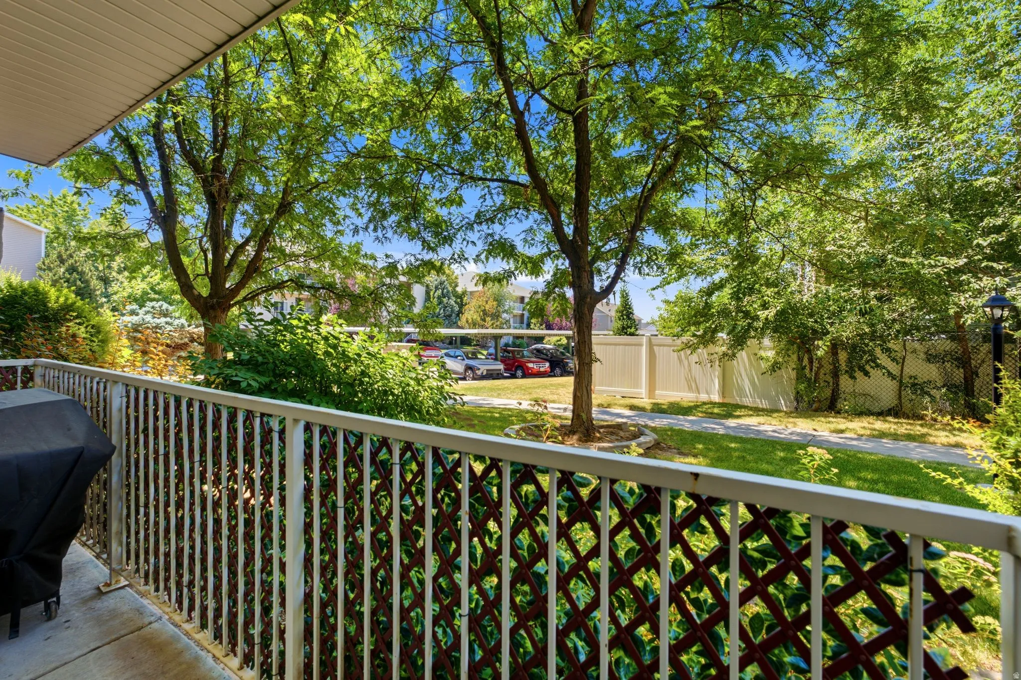 Private patio space featuring a white slatted railing with decorative lattice