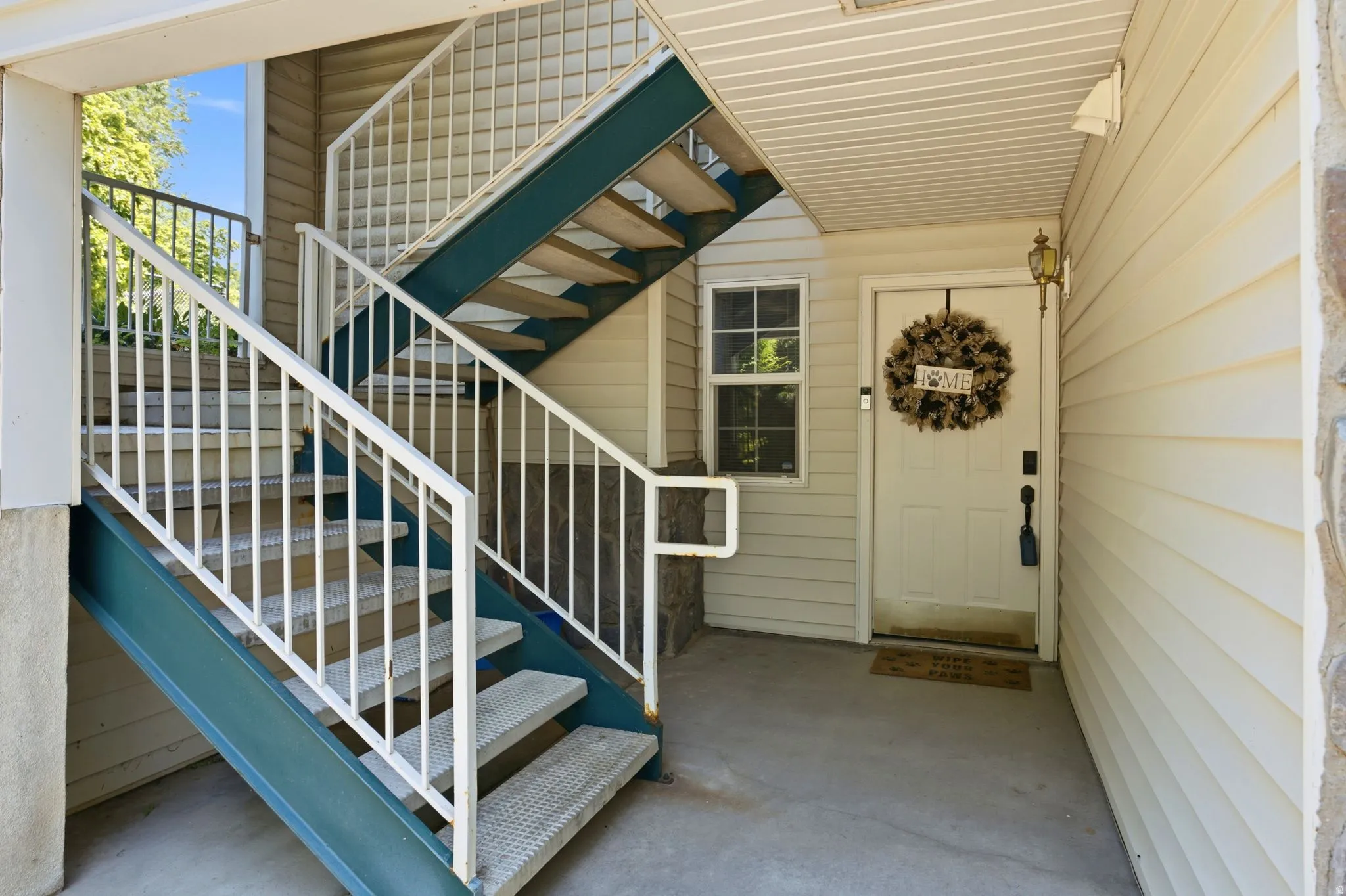 Ground-level entry featuring a white paneled door, exterior wall lantern, and a concrete landing