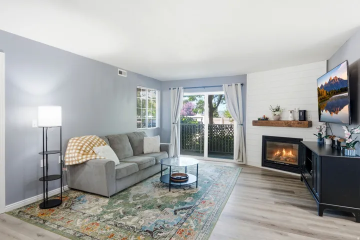 Living area featuring wood-finish flooring, a shiplap accent wall, and a built-in gas fireplace with a wood mantle