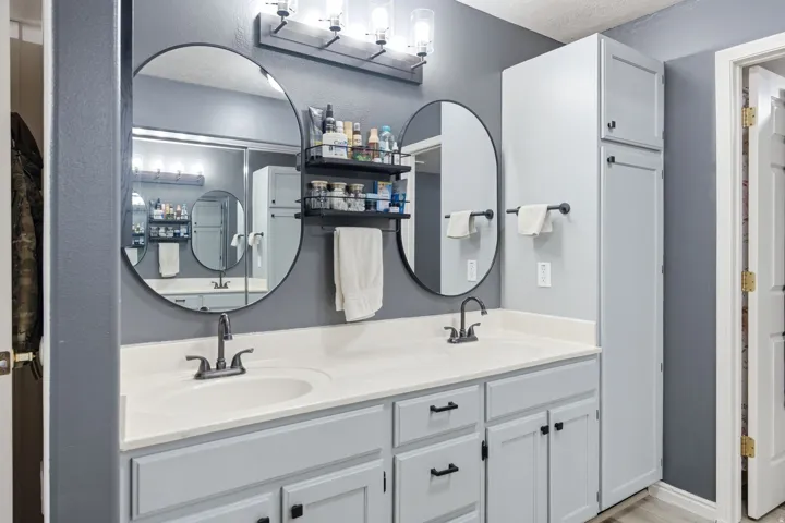 Master bath with a double vanity with light gray cabinetry and white countertops
