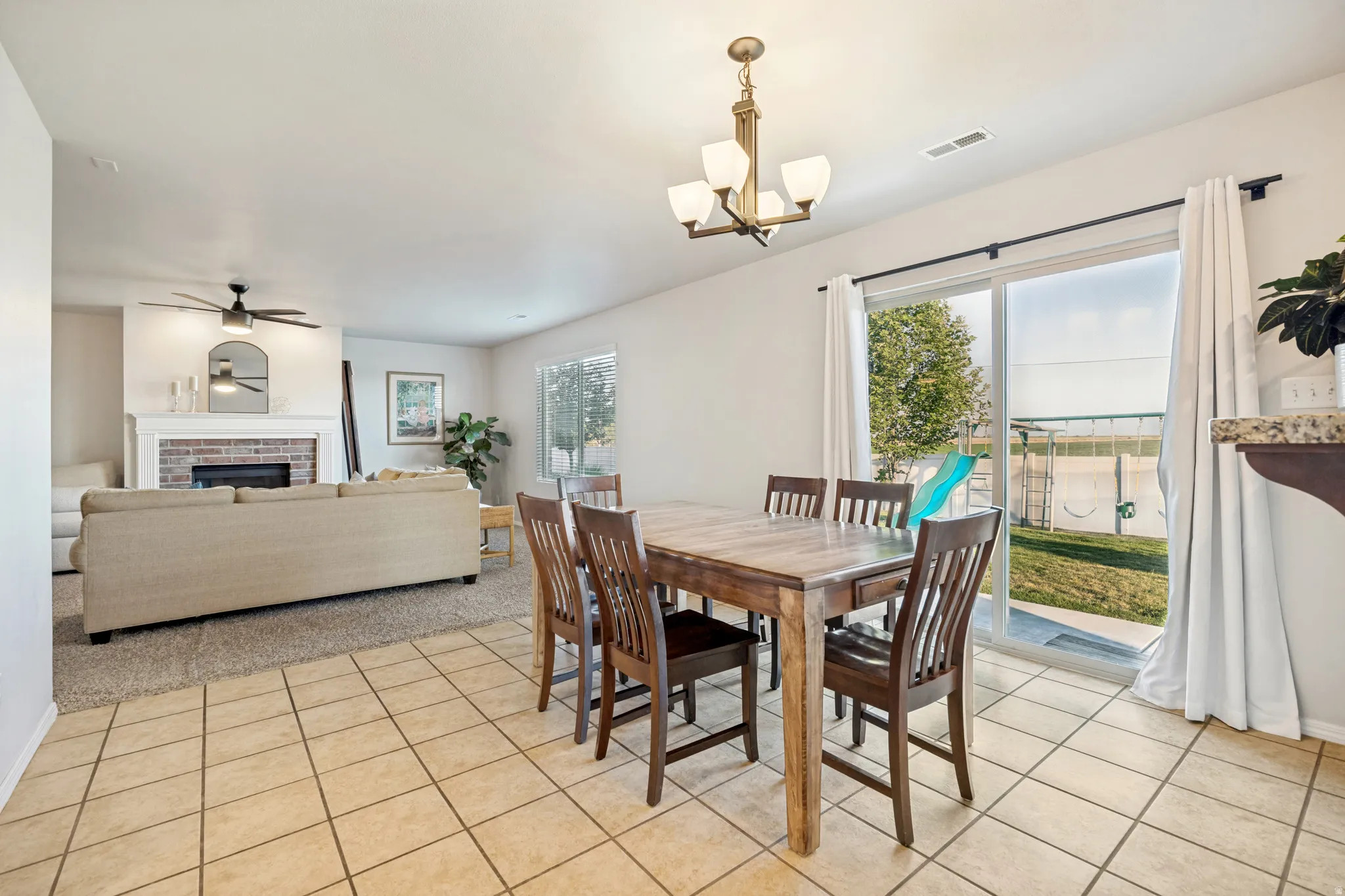 Open-concept dining area featuring tile flooring, a bronze-finish chandelier, and sliding glass doors opening to the backyard