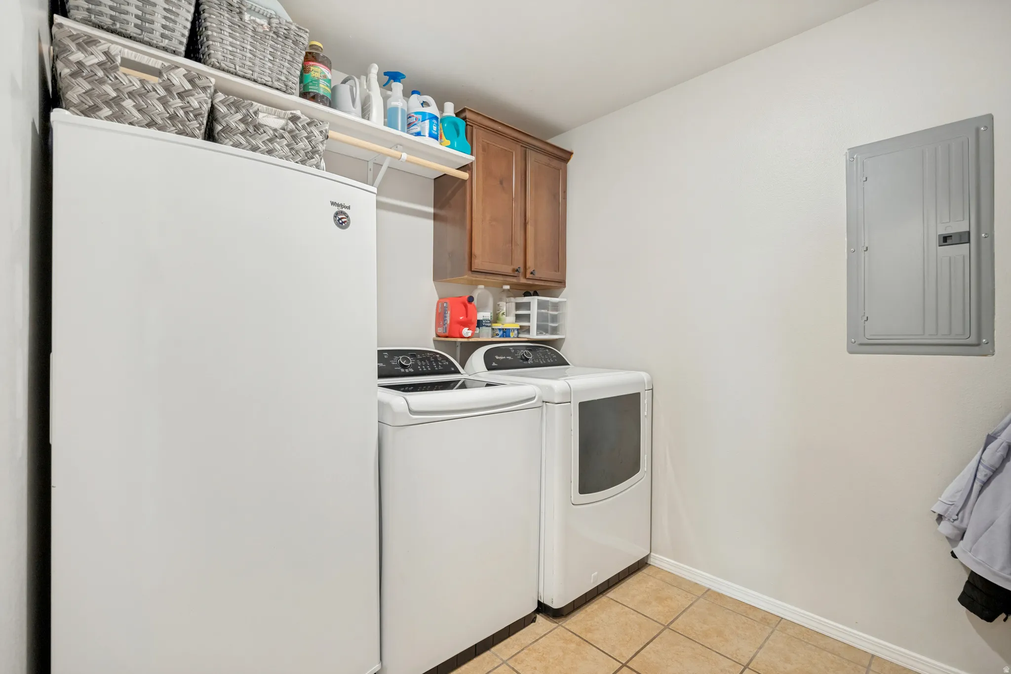 Dedicated laundry area featuring tile flooring, a built-in wooden cabinet, and a wall-mounted shelving unit
