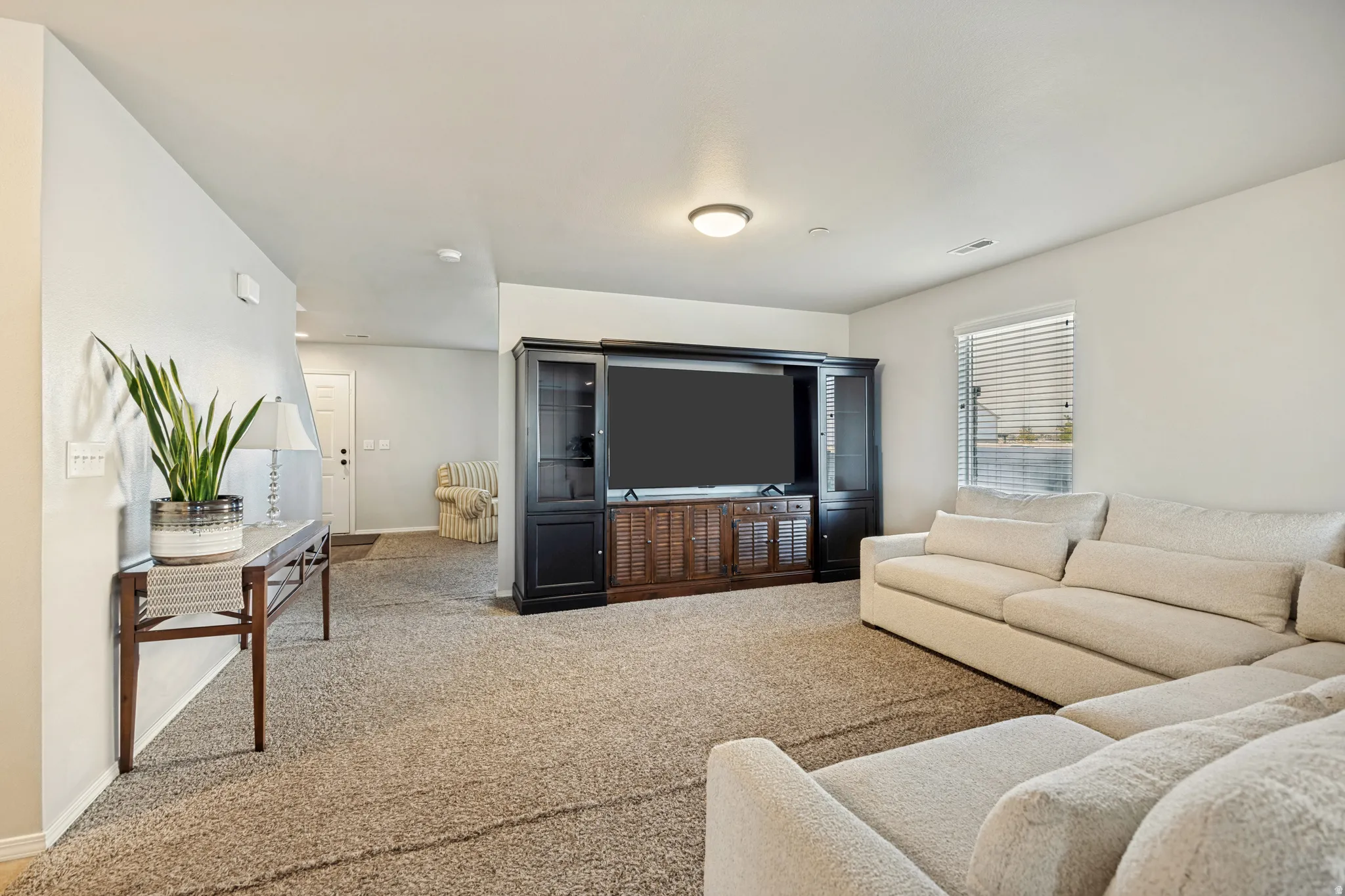 Carpeted living area featuring a single window with blinds and recessed lighting