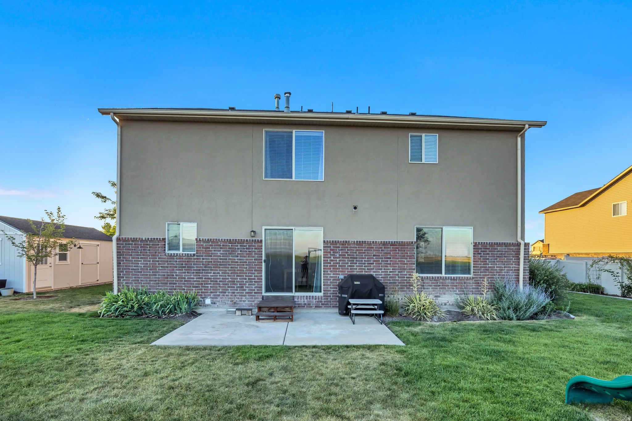 Spacious backyard featuring a concrete patio, sliding glass door access, and a brick and stucco exterior