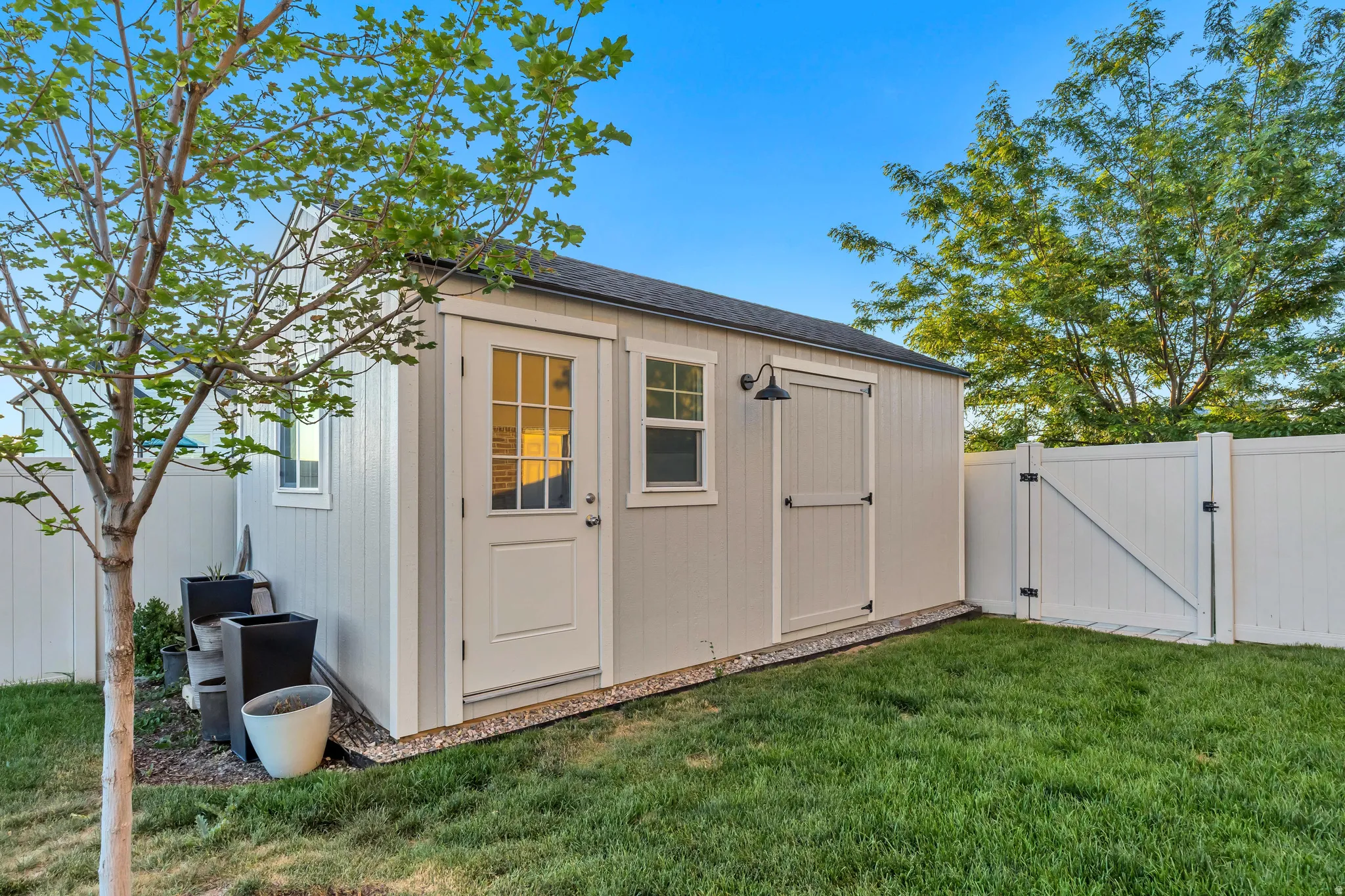 Detached storage shed with a panel door, transom window, and a built-in light fixture