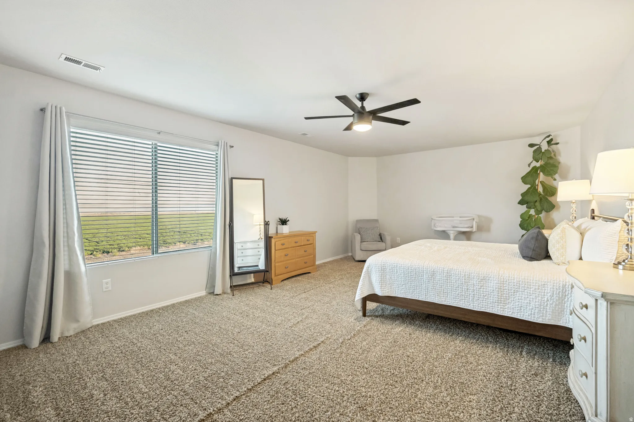 Spacious room featuring neutral carpeting, light-toned walls, and a ceiling fan with integrated lighting