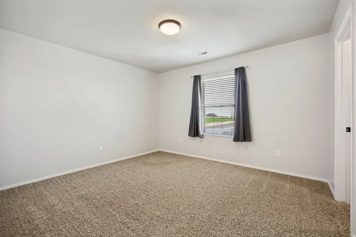 Carpeted flooring, window with blinds, ceiling-mounted light fixture, and white painted walls