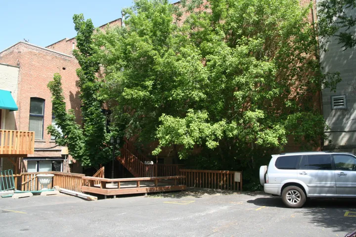 Paved parking area with a wood deck and ramp leading to an exterior staircase