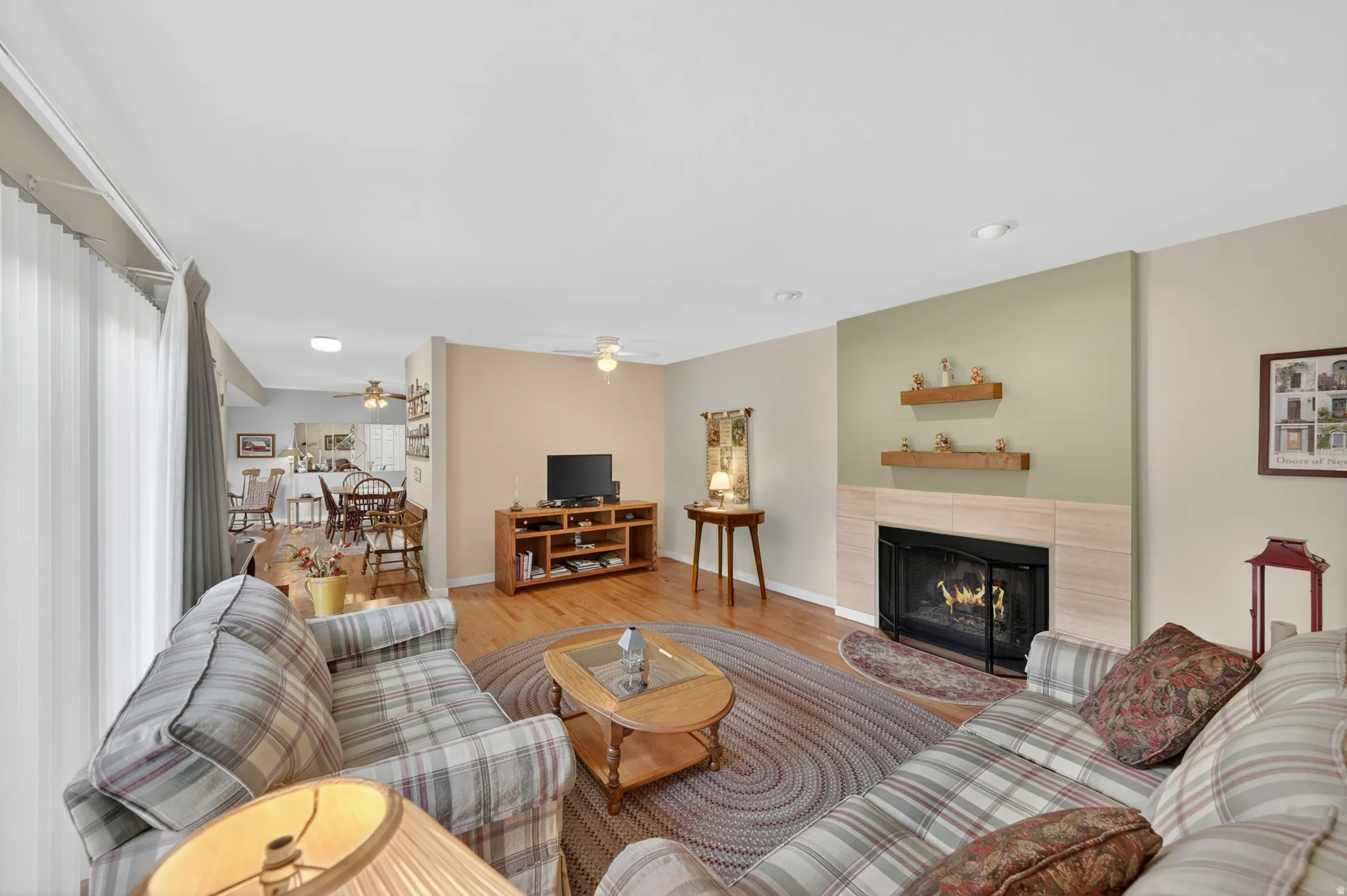 Living area featuring natural oak wood flooring and a fireplace with a light-toned surround