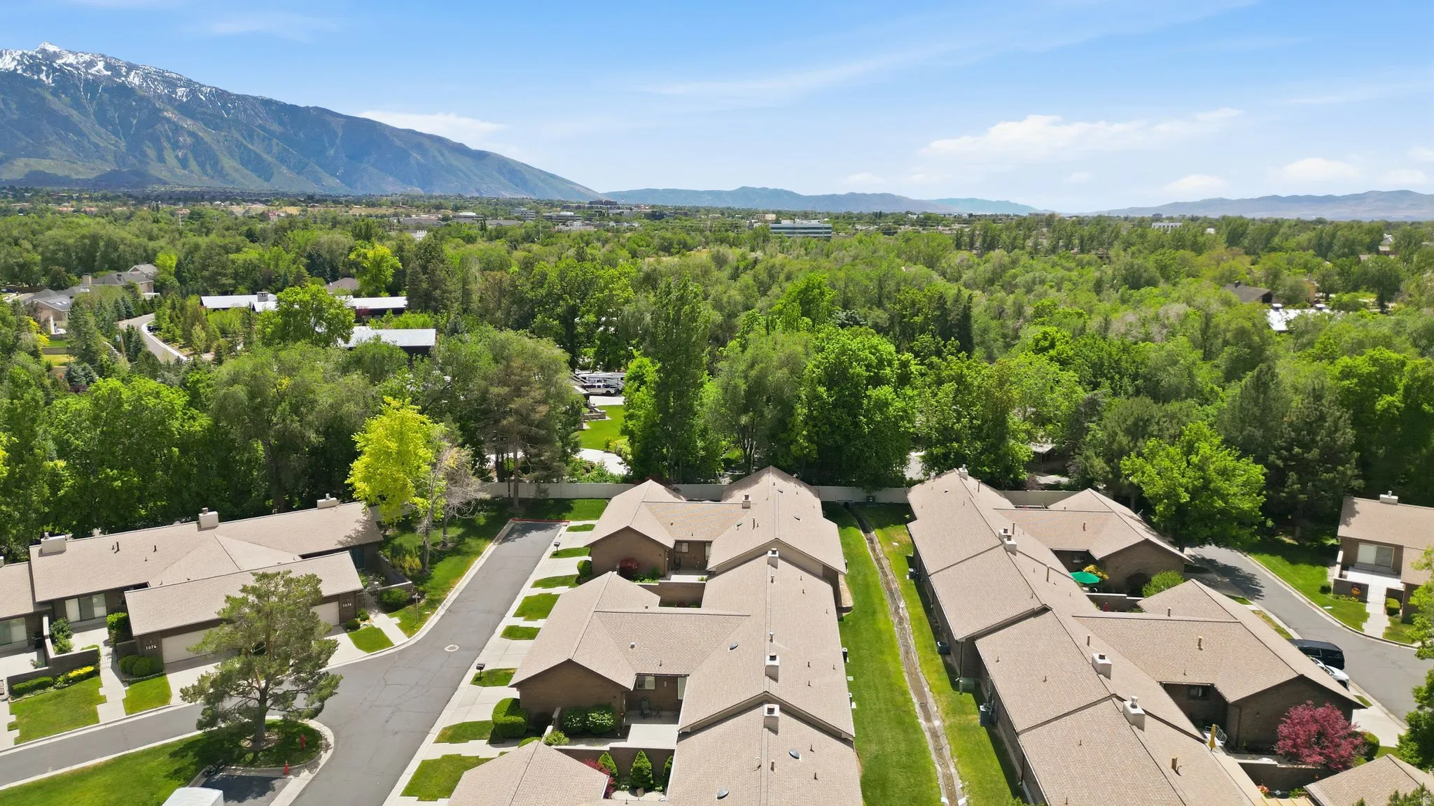 Community setting featuring residential buildings with brown shingle roofs and brick facades