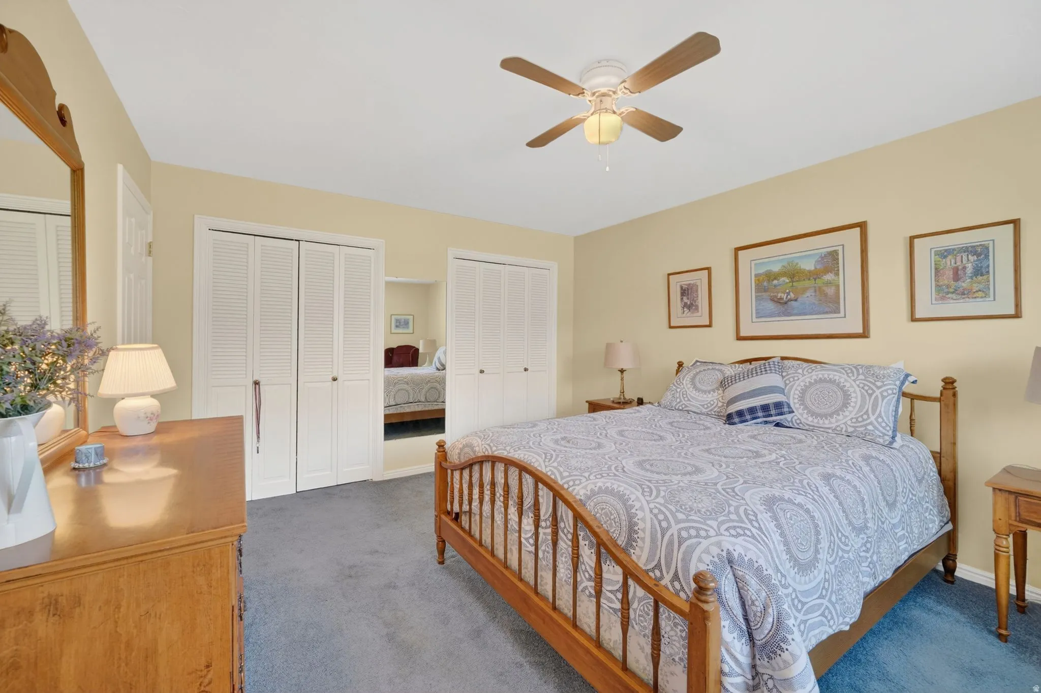 Bedroom featuring a ceiling fan with integrated lighting, soft yellow wall paint, and blue carpeting
