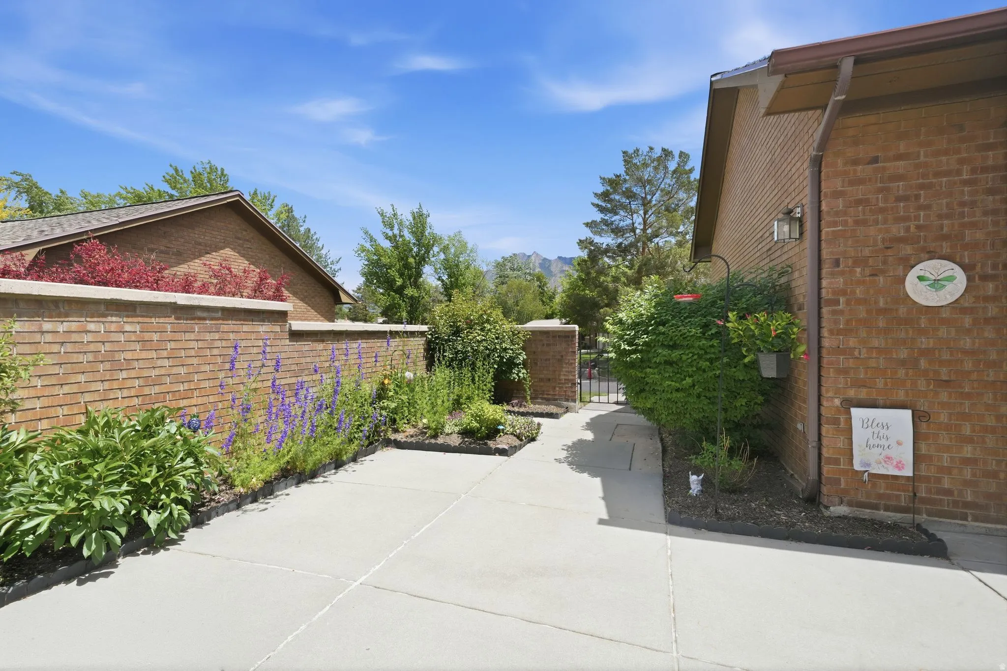 Brick exterior with an angled roofline, concrete pathway, and landscaped garden beds