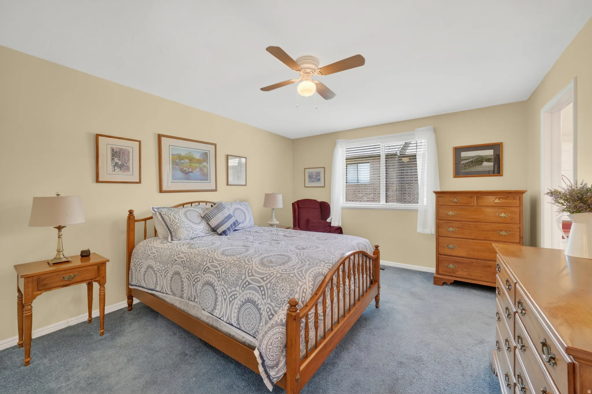 Carpeted room featuring a ceiling fan with light fixture, window with blinds, and light-toned walls