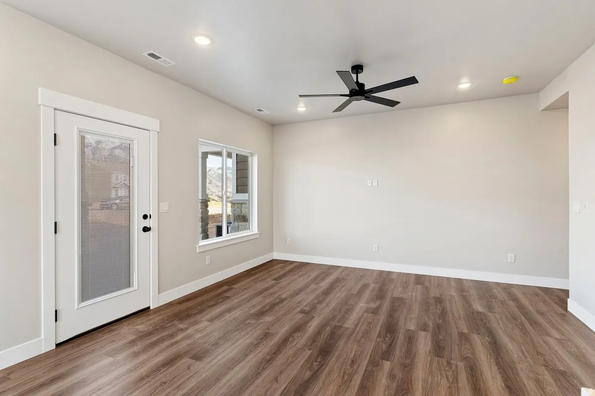Spacious room featuring wood-finish flooring, a contemporary ceiling fan, recessed lighting, and a glass-paneled door