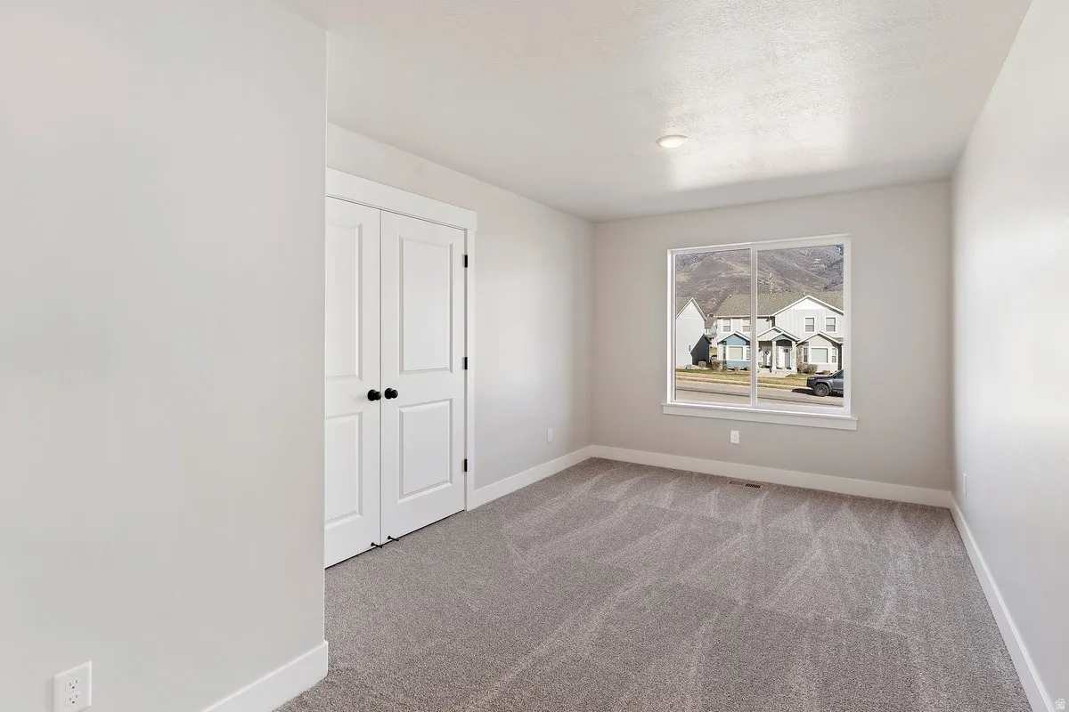 Carpeted room featuring a large window, white trim, and a double-door closet
