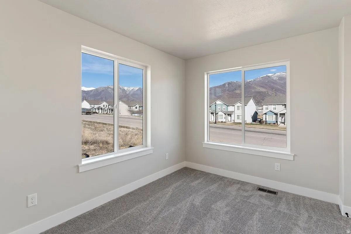 Spacious room featuring two large windows with white trim, light gray walls, and gray carpet flooring