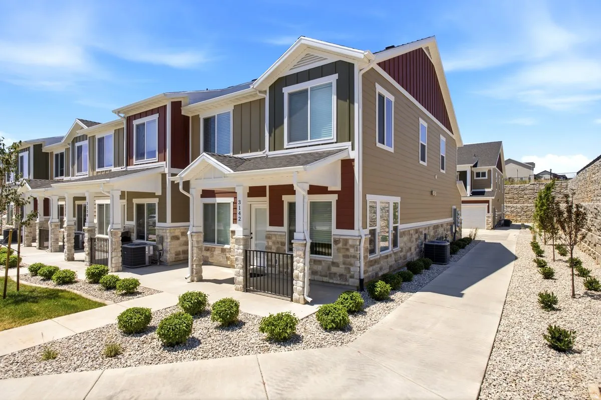 Modern townhome exterior featuring multi-toned siding, stone accents, white trim, and a covered porch
