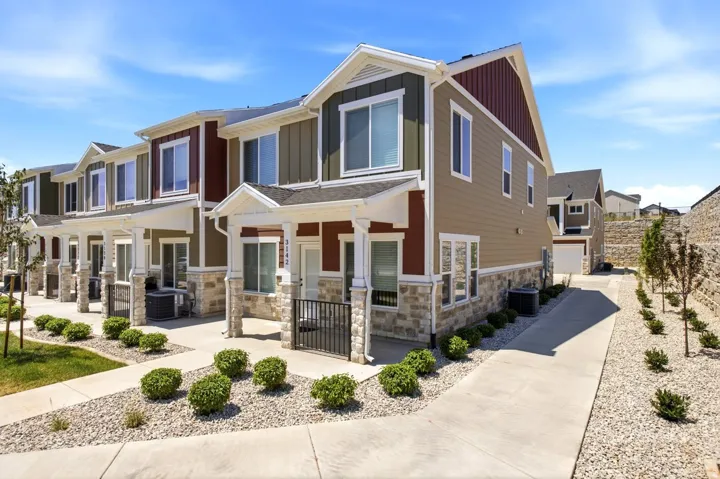 Modern townhome exterior featuring multi-toned siding, stone accents, white trim, and a covered porch