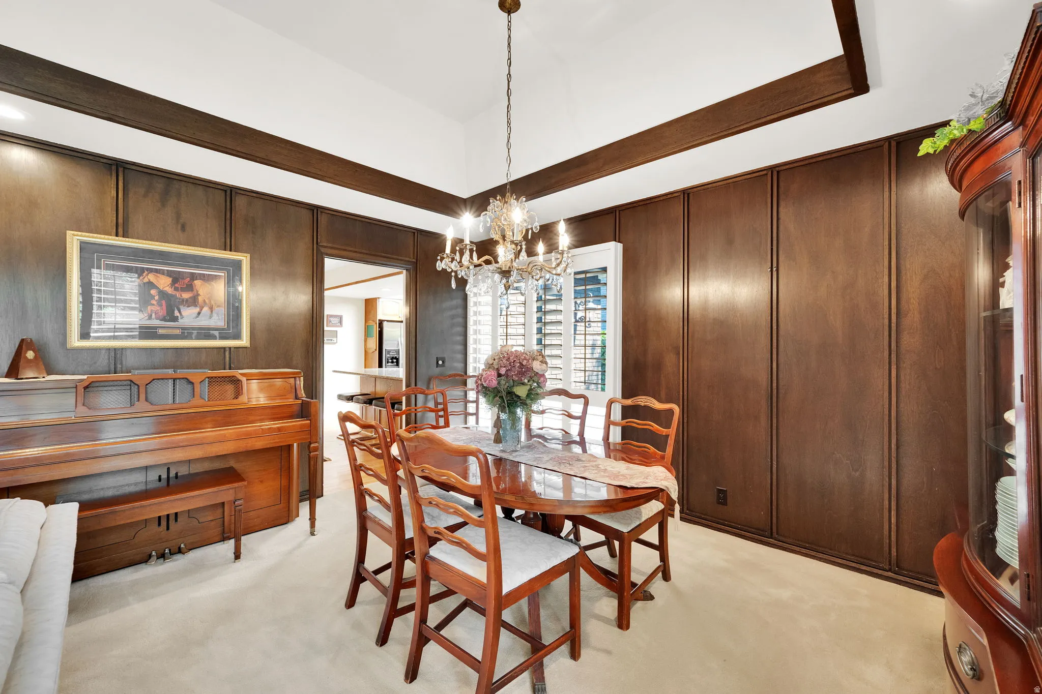 Dining area featuring wood paneling, a vaulted ceiling with exposed wood beams, and a crystal chandelier
