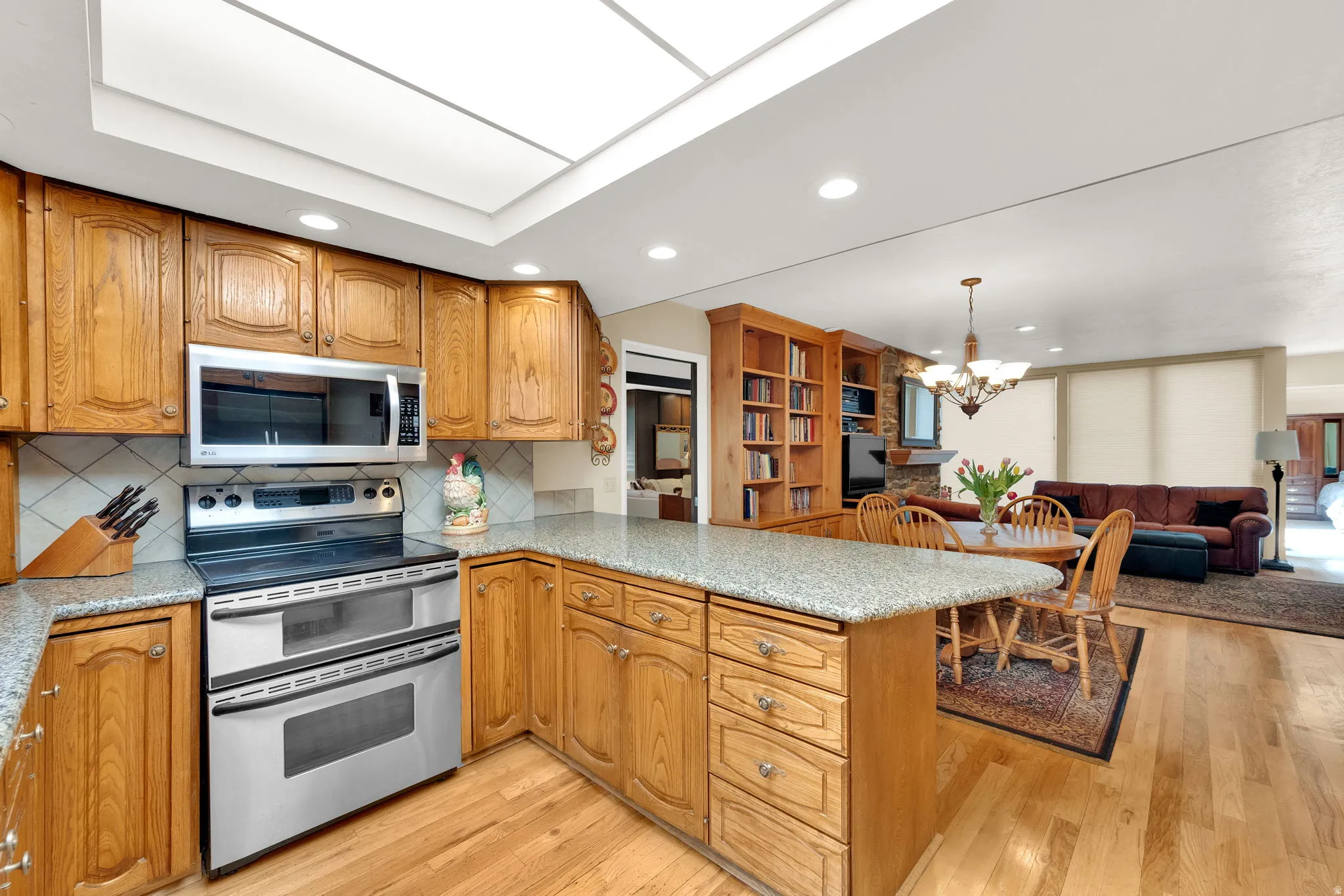 Kitchen featuring wood cabinetry, stainless steel appliances, granite-style countertops, and tile backsplash