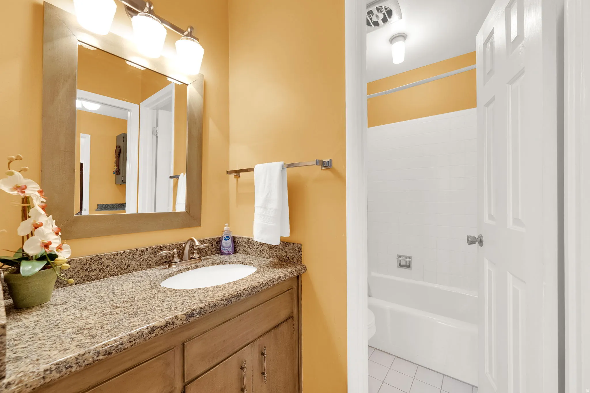 Bathroom featuring a vanity with a granite-style countertop, undermount sink, and brushed nickel faucet