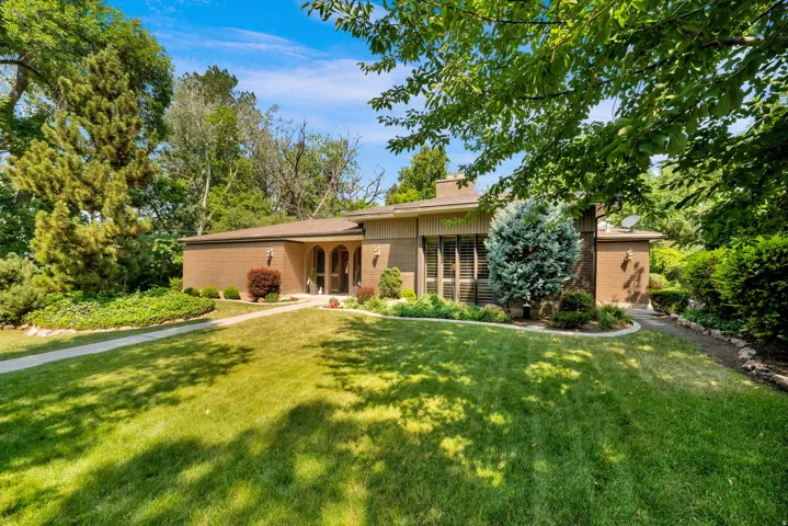 Brick exterior residence featuring a front lawn and mature trees