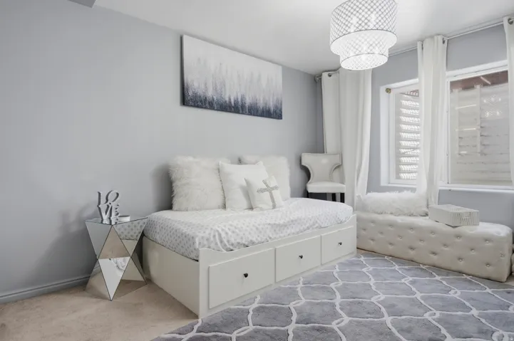 Carpeted room featuring light gray walls, a built-in bed frame with drawer storage, and a tufted bench with button detailing