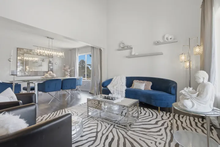 Open-concept living space featuring high ceilings, wood-finish flooring, and bright natural light from a large window