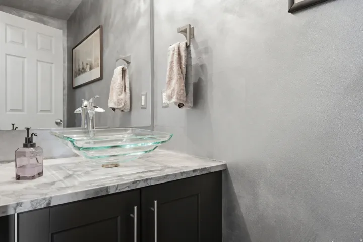 Bathroom vanity featuring a glass vessel sink, chrome faucet, and stone-finish countertop