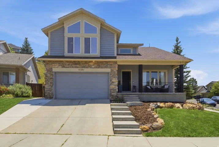 Contemporary exterior featuring stone accents, a covered porch with dark columns, and a prominent second-story window array
