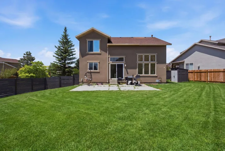 Spacious backyard featuring a large grass lawn, a concrete patio, and a dark horizontal slat fence