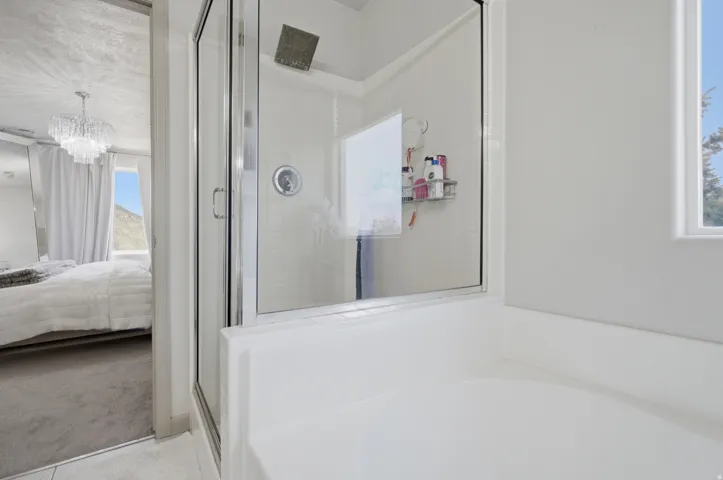 Glass-enclosed shower with a rainfall showerhead, white tile surround, and built-in shelving