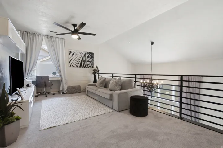 Loft area with sloped ceiling, featuring a contemporary ceiling fan, and built-in desk with window