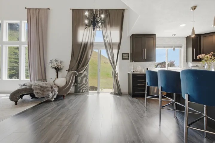 Open-concept living space featuring wood-finish flooring, a sliding glass door, and large picture windows