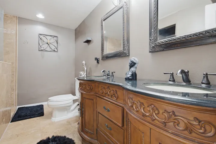 Double vanity with an ornate wood-finish cabinet, dark countertop, and two framed mirrors