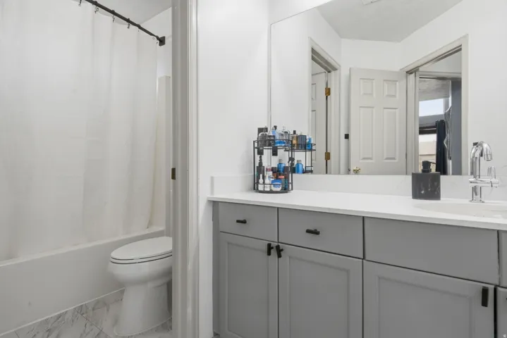 Bathroom featuring a white bathtub, toilet, and a vanity with a white countertop and gray cabinetry