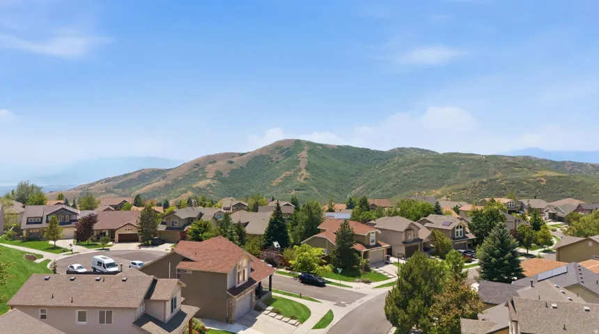 Residential neighborhood with diverse home styles, surrounded by rolling hills and distant mountains