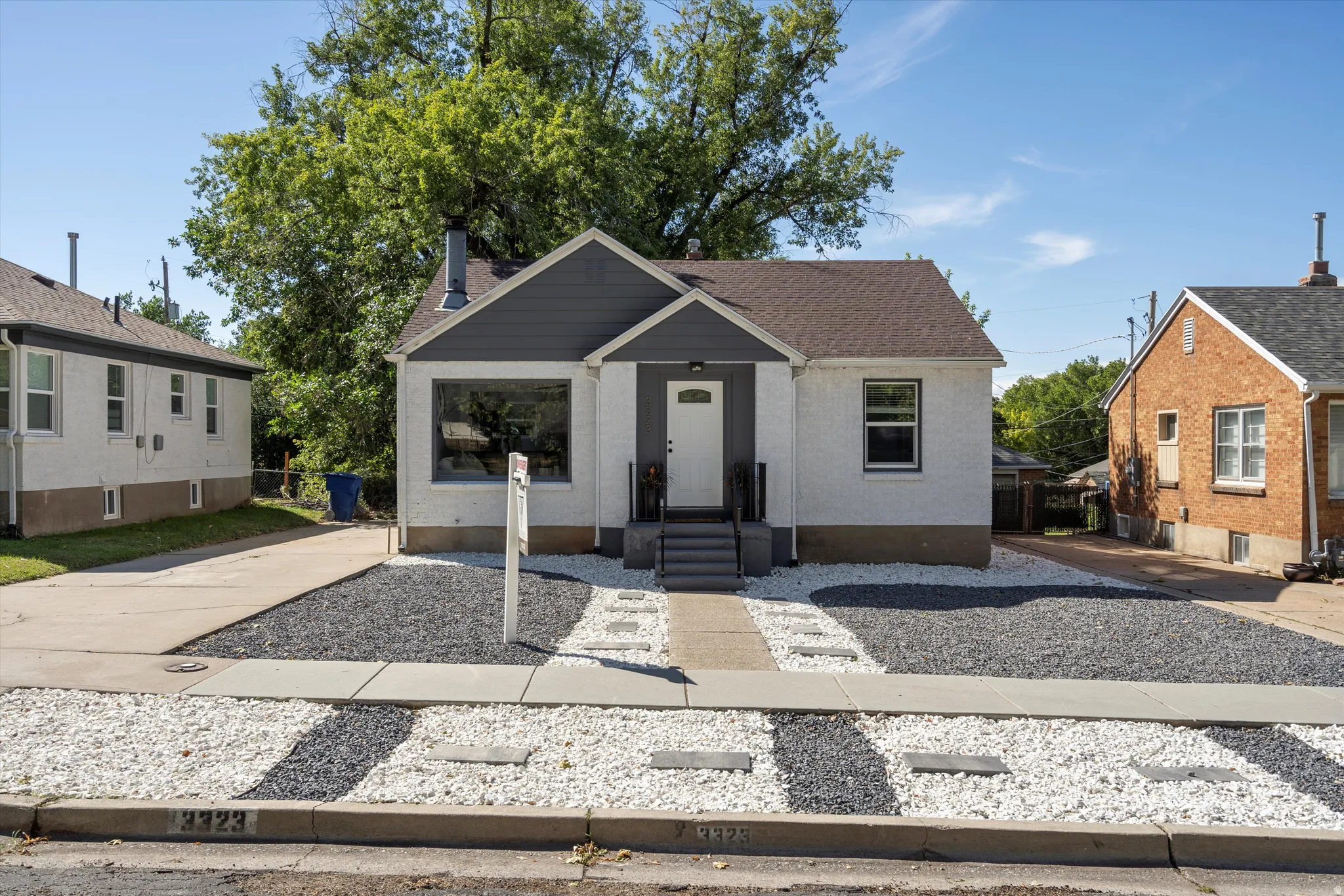 Contemporary facade featuring white stucco, dark gray siding, and a contrasting brown shingle roof