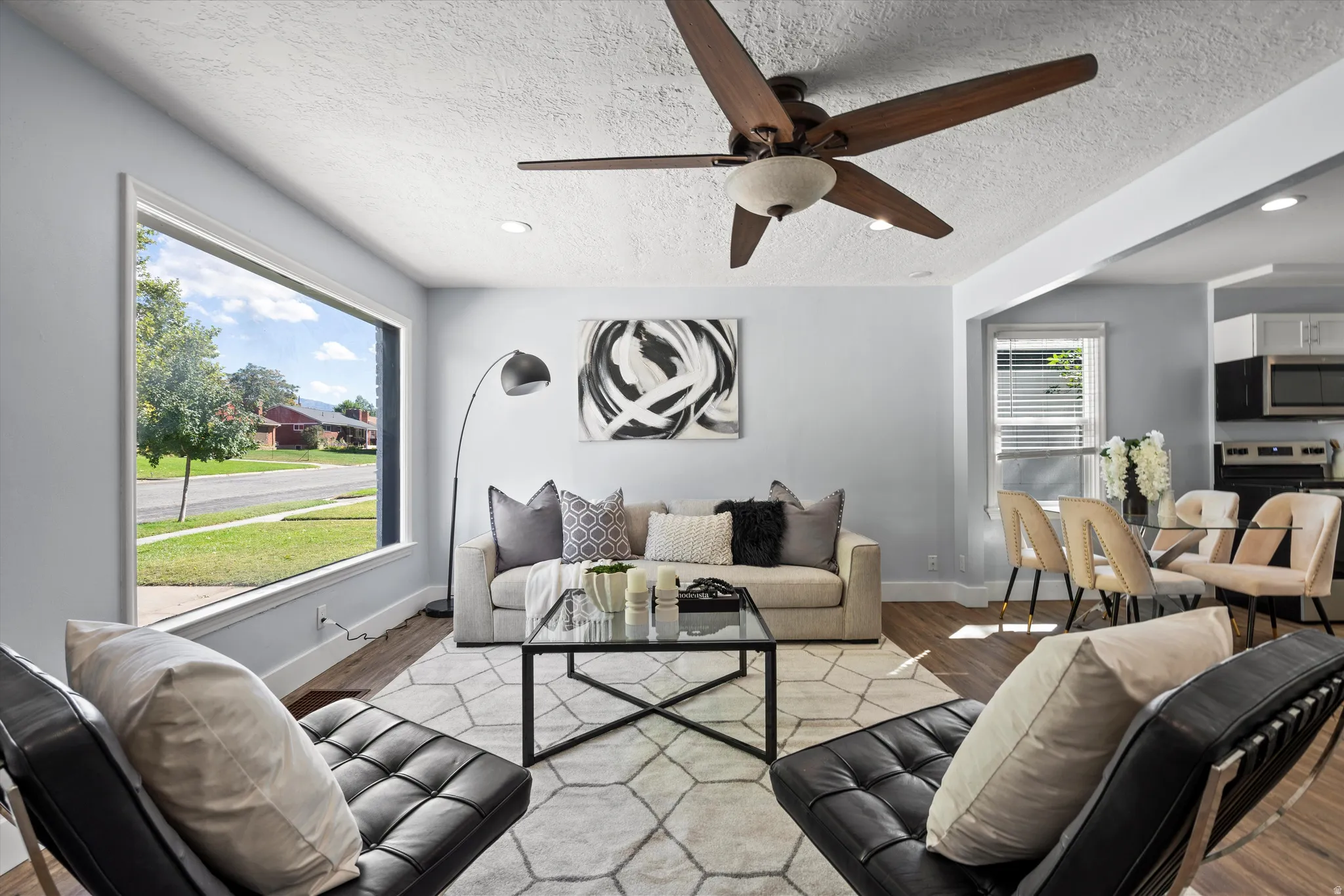 Spacious living area featuring a large picture window, wood-finish flooring, recessed lighting, and a modern ceiling fan